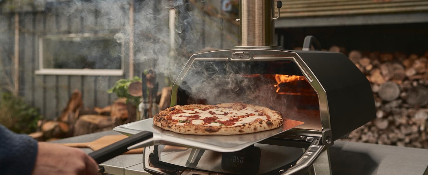 Sliding a fresh Neapolitan pizza into the Ooni Karu 2 Pro oven over an open flame
