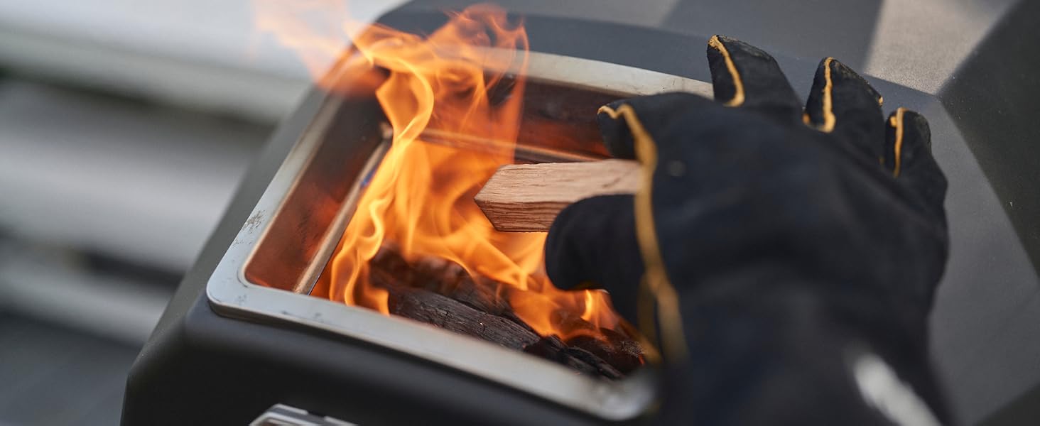 Adding wood logs to the Ooni Karu 2 Pro fuel firebox with flames visible