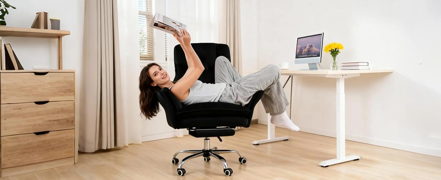 Woman reclined in black chair reading a magazine above her head at a standing desk