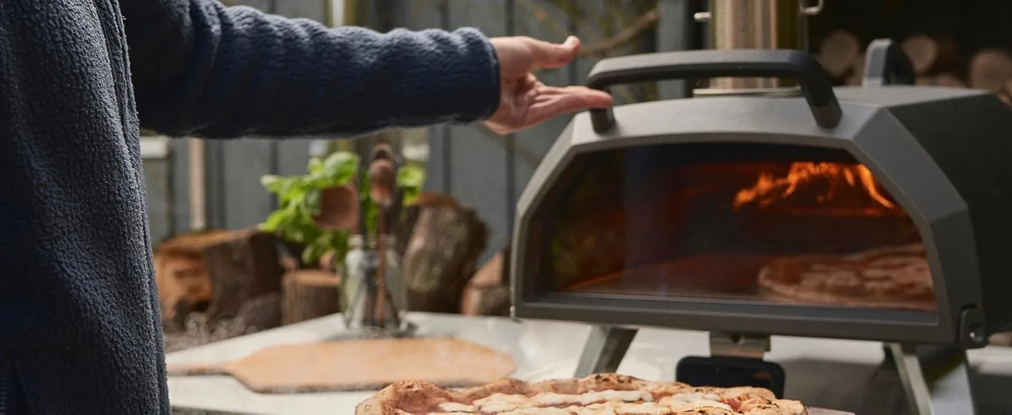 Opening the glass door of the Ooni Karu 2 Pro to check on a pizza inside