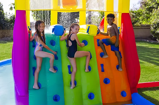 Children climbing the three-lane inflatable climbing wall with padded blue grips