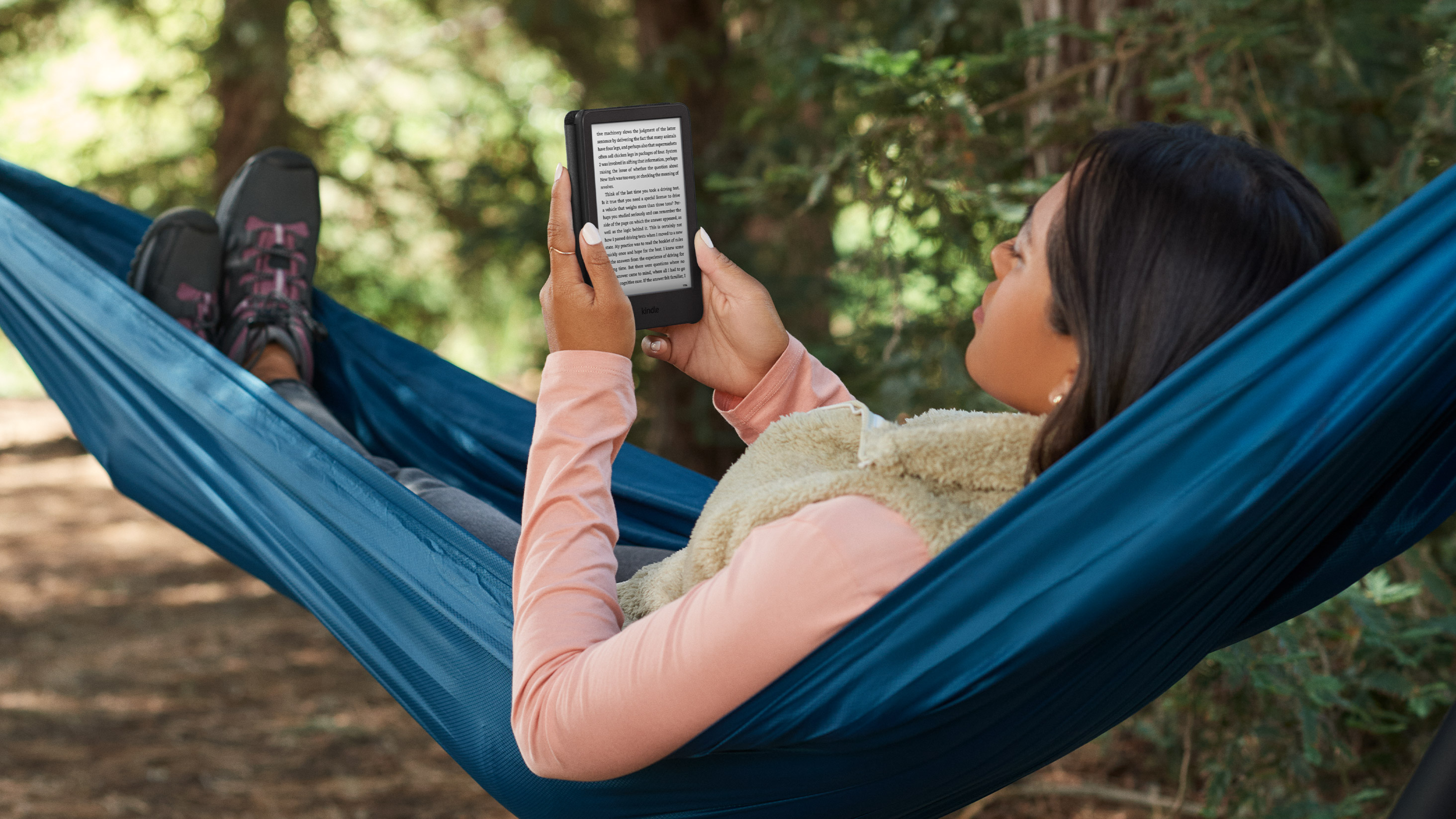 Woman reading on a Kindle while laying in a hammock outside