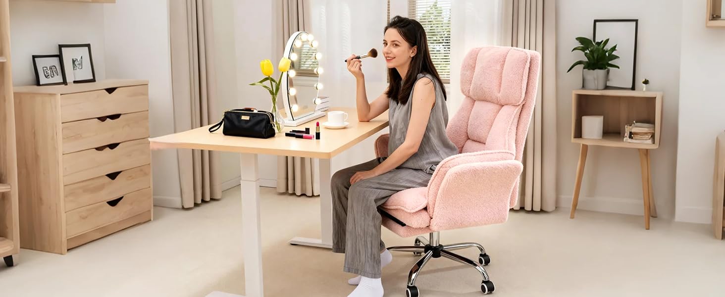 Woman applying makeup in a pink teddy-fabric chair at a vanity desk with LED mirror