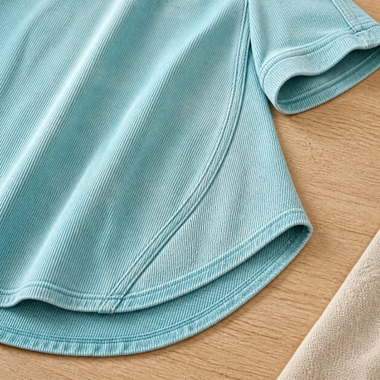 Close view of the curved hem side seam and short-sleeve cuff