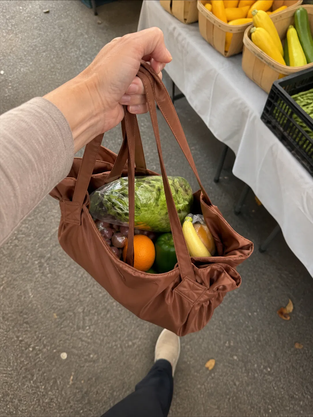 Customer holding the Brown tote filled with fresh groceries at a store