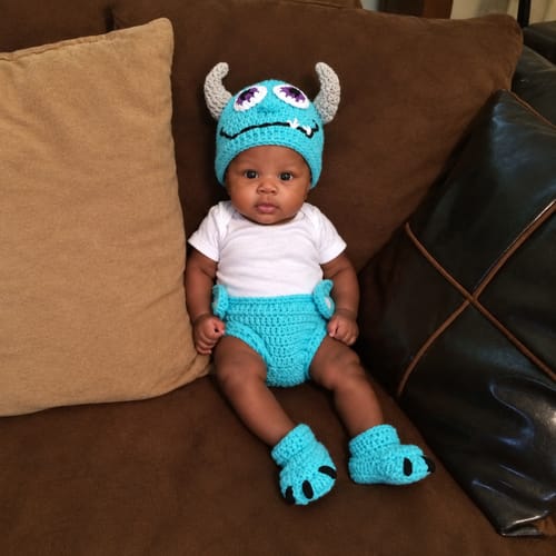 Blue Monster baby outfit styled on a sofa
