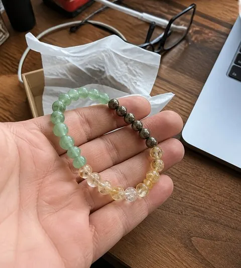 Man holding the Money Success bracelet at a home office desk