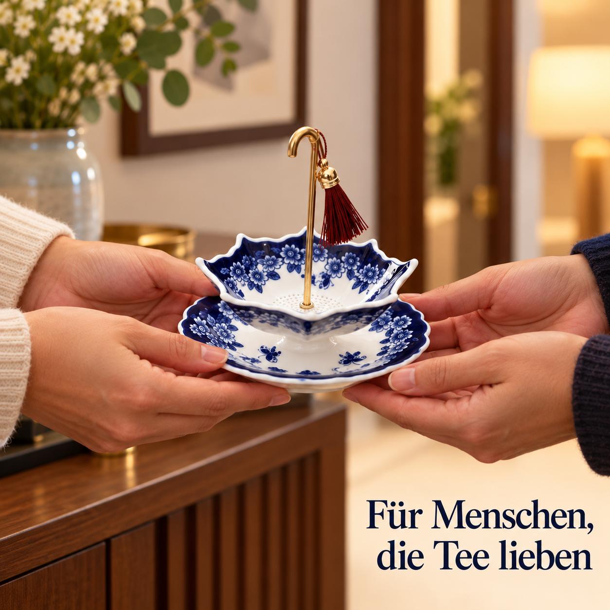 Ein Regenschirm-Teesieb mit passender Ablage wird als Geschenk von Händen überreicht