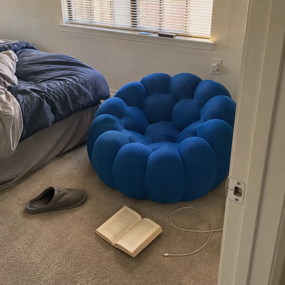 Blue Bubble Floor Sofa beside a bed with a book and slippers nearby
