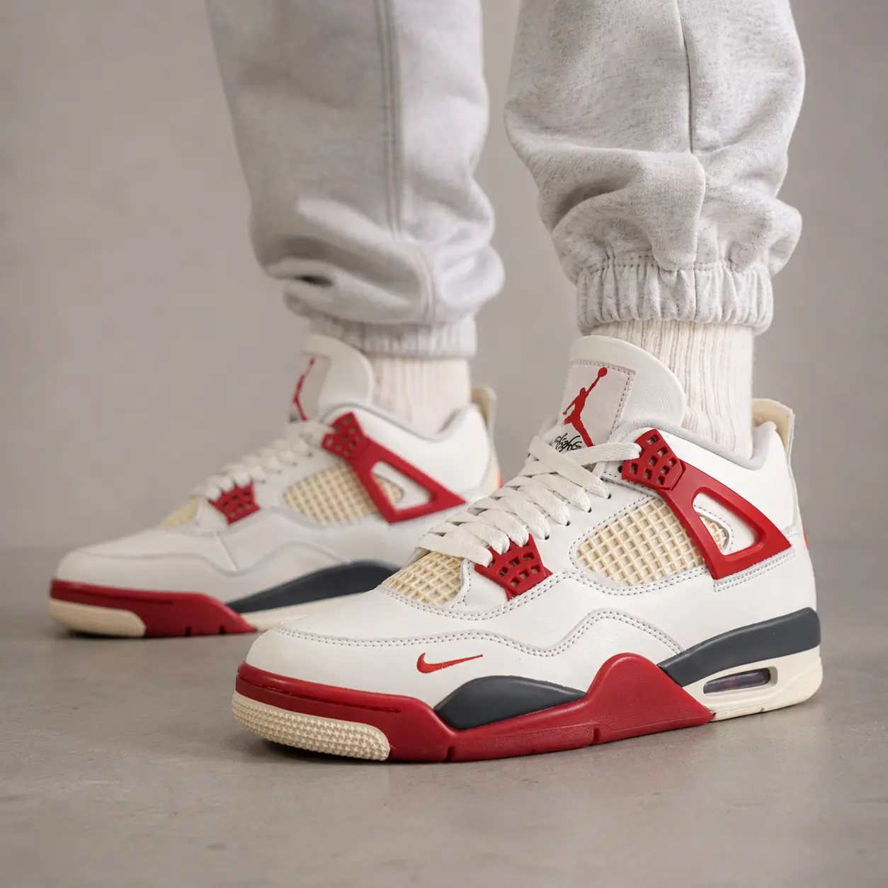 On-feet view of Jordan 4 Nigel Sylvester Brick After Brick Reps showing Sail leather and Cinnabar red accents