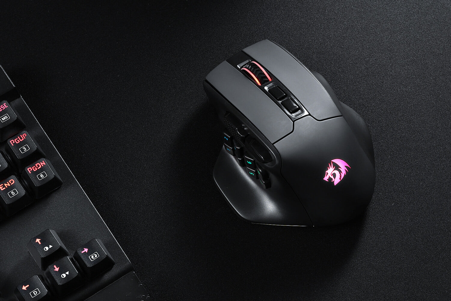 AATROX M811 PRO mouse on a black mouse pad next to a mechanical gaming keyboard, showing RGB lighting.