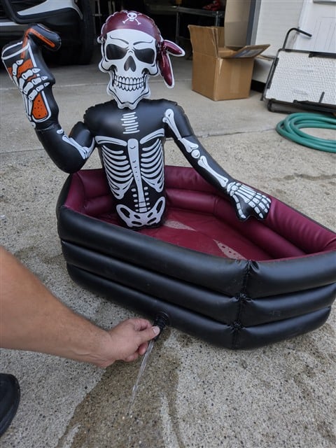 Melted ice water draining from a pirate skeleton cooler on a driveway