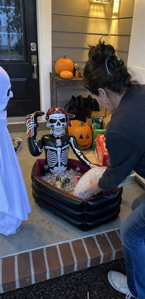 Family loading ice into a pirate skeleton cooler on a front porch