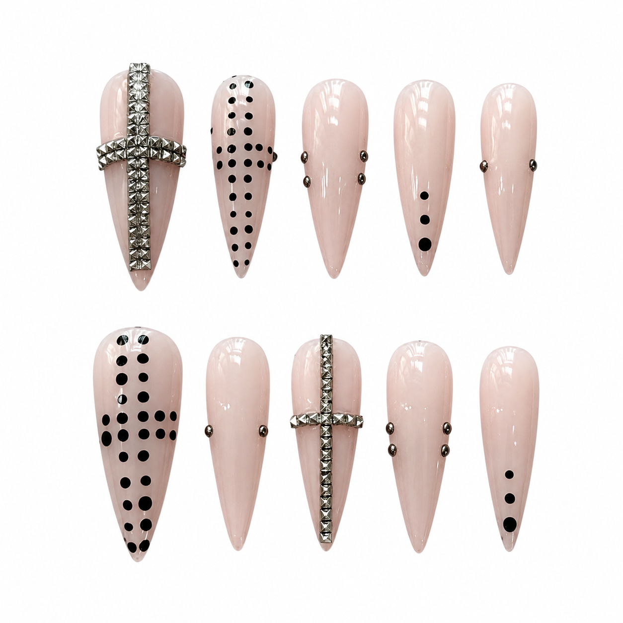 Stiletto press-on nails in glossy blush pink accented with a large textured silver cross, black dot patterns, and small metal studs.