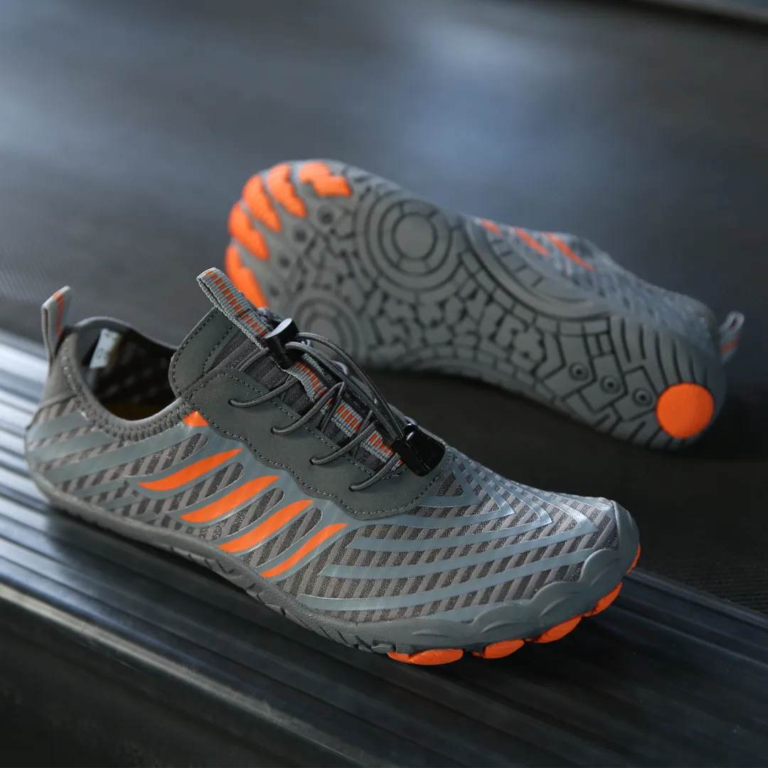 Graue und orange Grounded Footwear Schuhe, die die flexible Traktionssohle zeigen