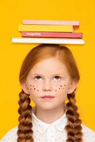Freckled child balancing books