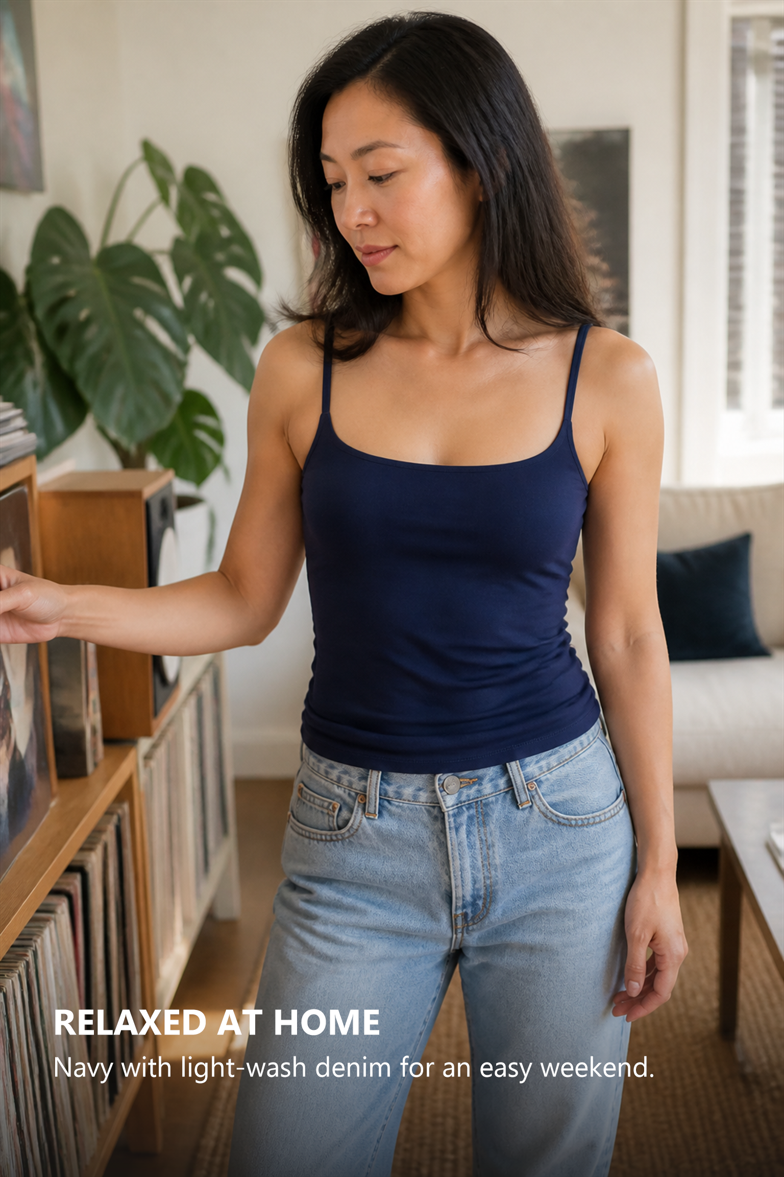Adult woman wearing the smooth navy camisole with light denim in a relaxed living room