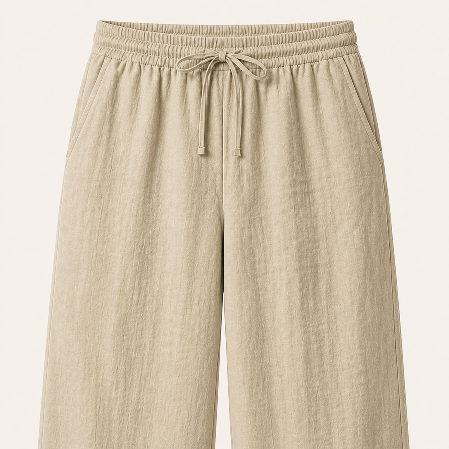 Large light-khaki front detail showing the gathered waistband, centered drawstring, side-pocket entrances and upper legs