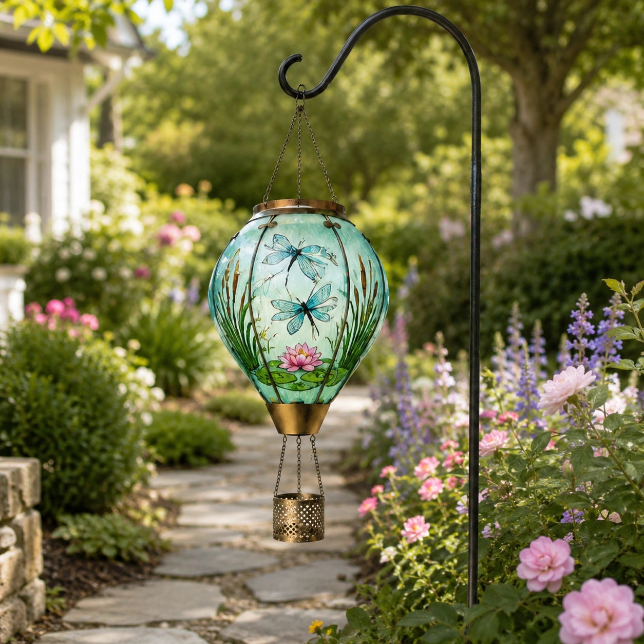 Dragonfly and lotus hot air balloon solar lantern hanging from a shepherd hook beside a garden path