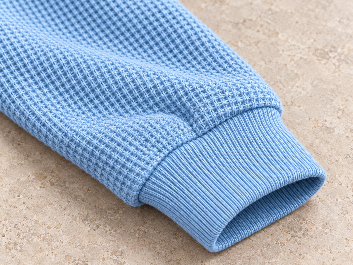 Illustrative close-up of the ribbed sleeve cuff and wool knit texture
