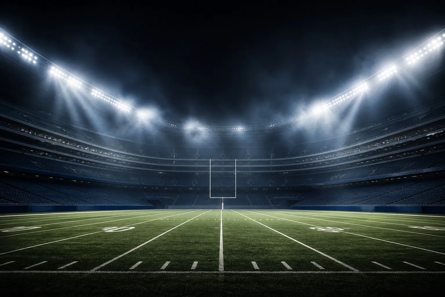 Dramatic empty NFL football stadium at night under bright floodlights
