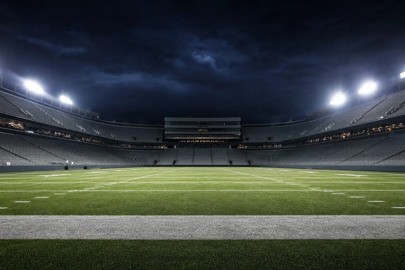 Dramatic empty college football stadium at night under bright floodlights