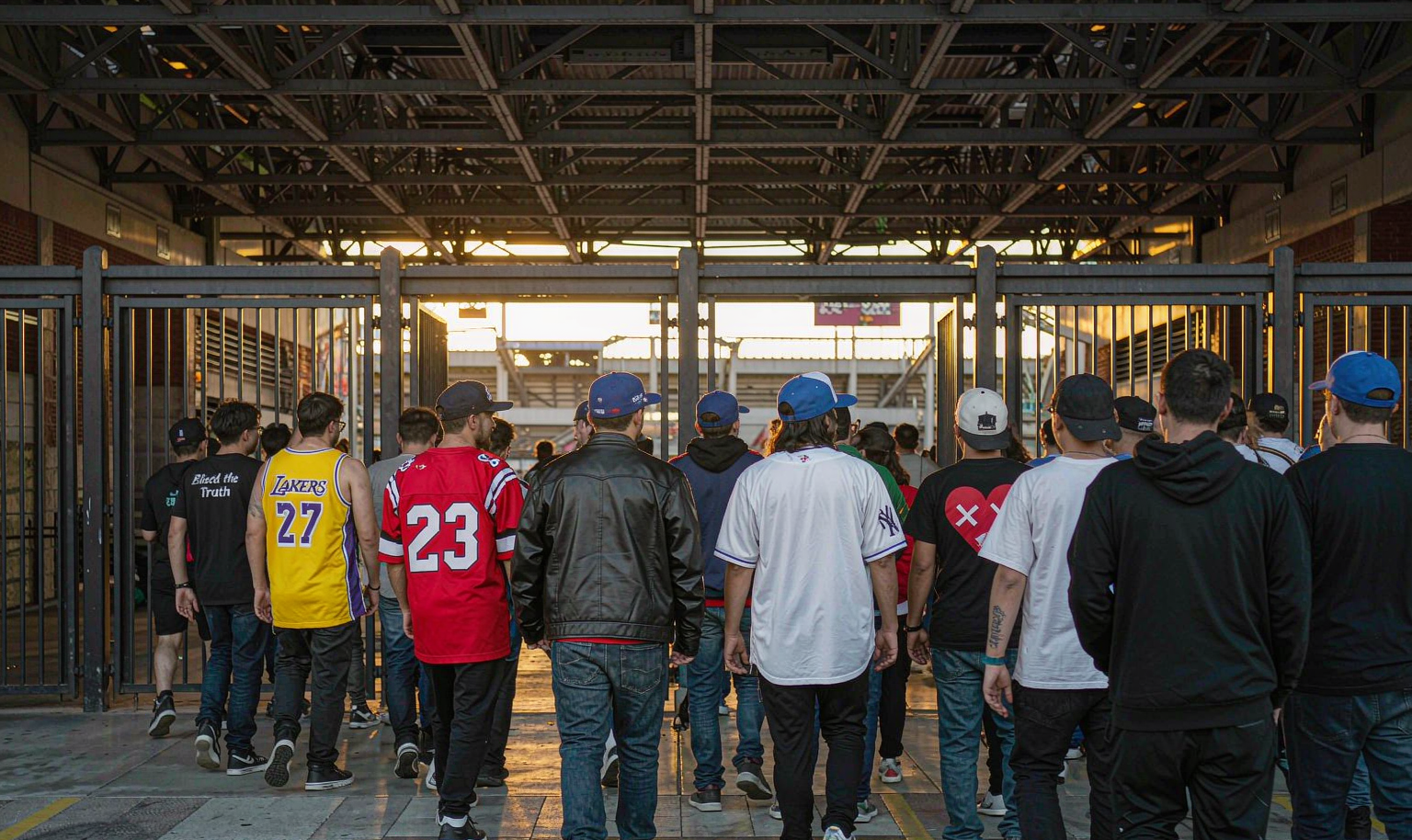 Fans in different team jerseys walking into a stadium on opening day