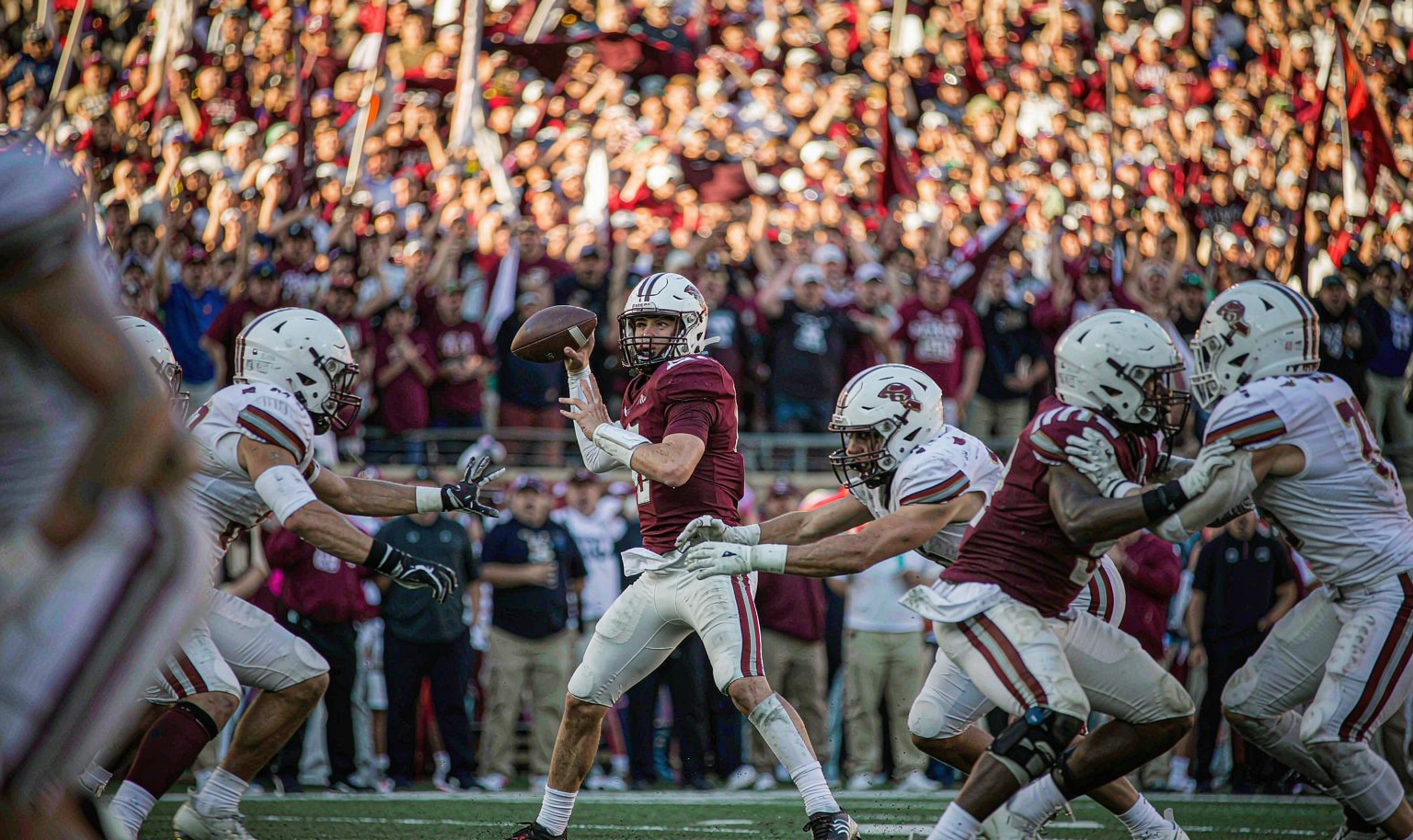 College football Saturday game action - quarterback dropping back to pass in a packed stadium