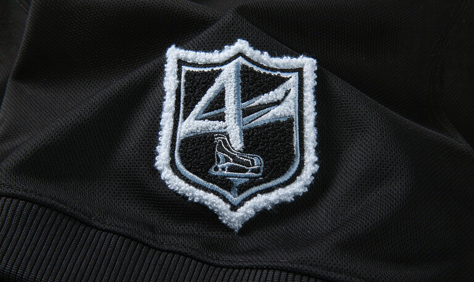 Woven team crest embroidery on a black hockey jersey - macro detail