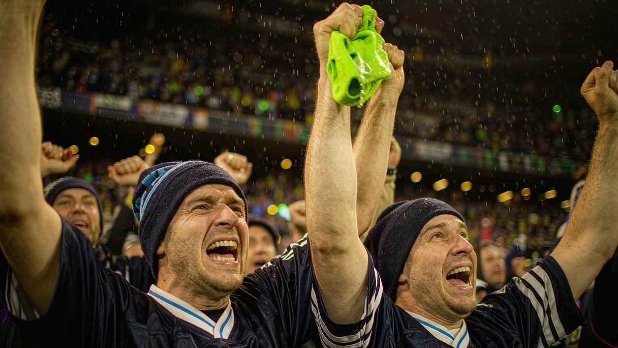 Seattle fans in navy jerseys celebrate under the lights on banner night