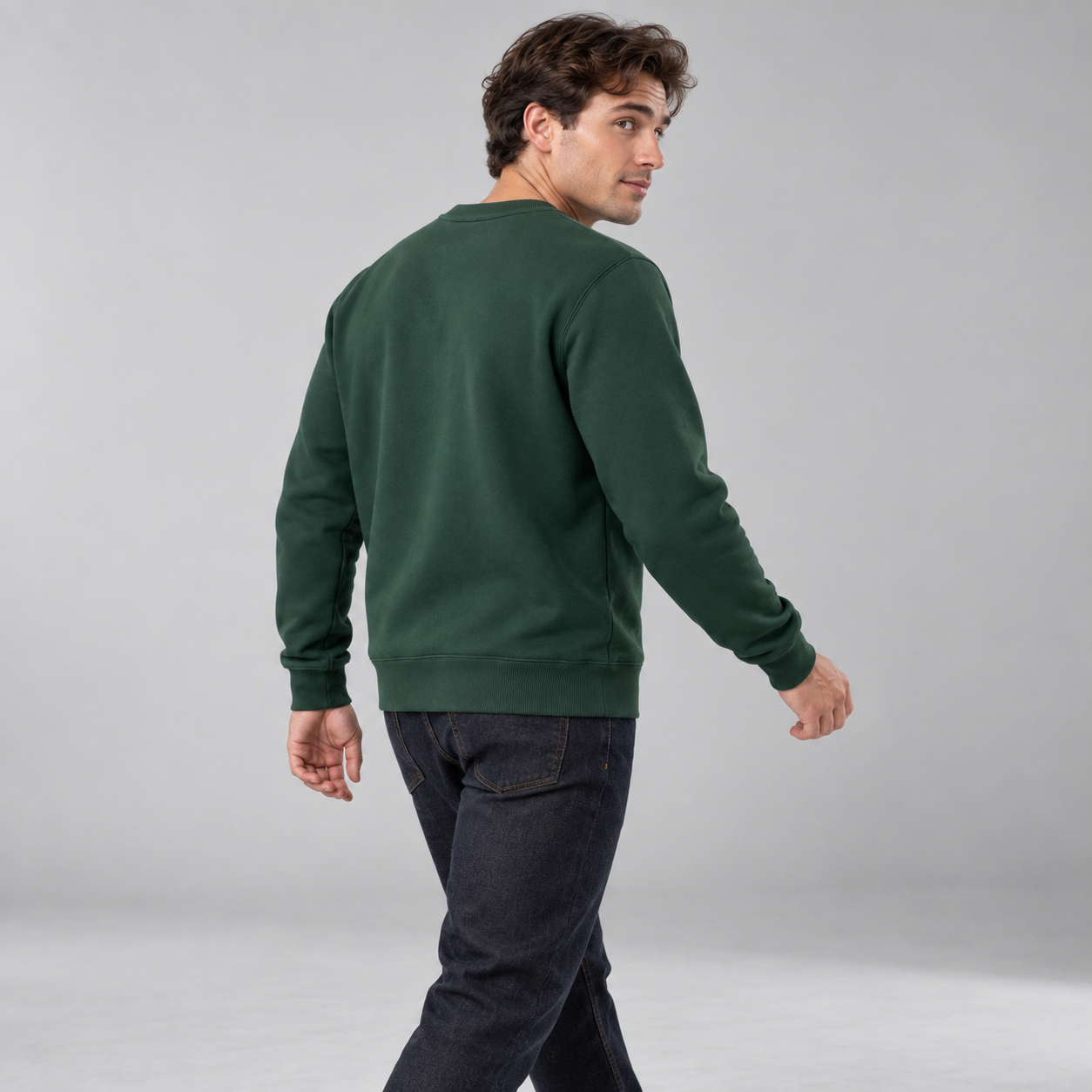 Young American male model wearing Deep Forest crewneck sweatshirt, moving back three-quarter studio view