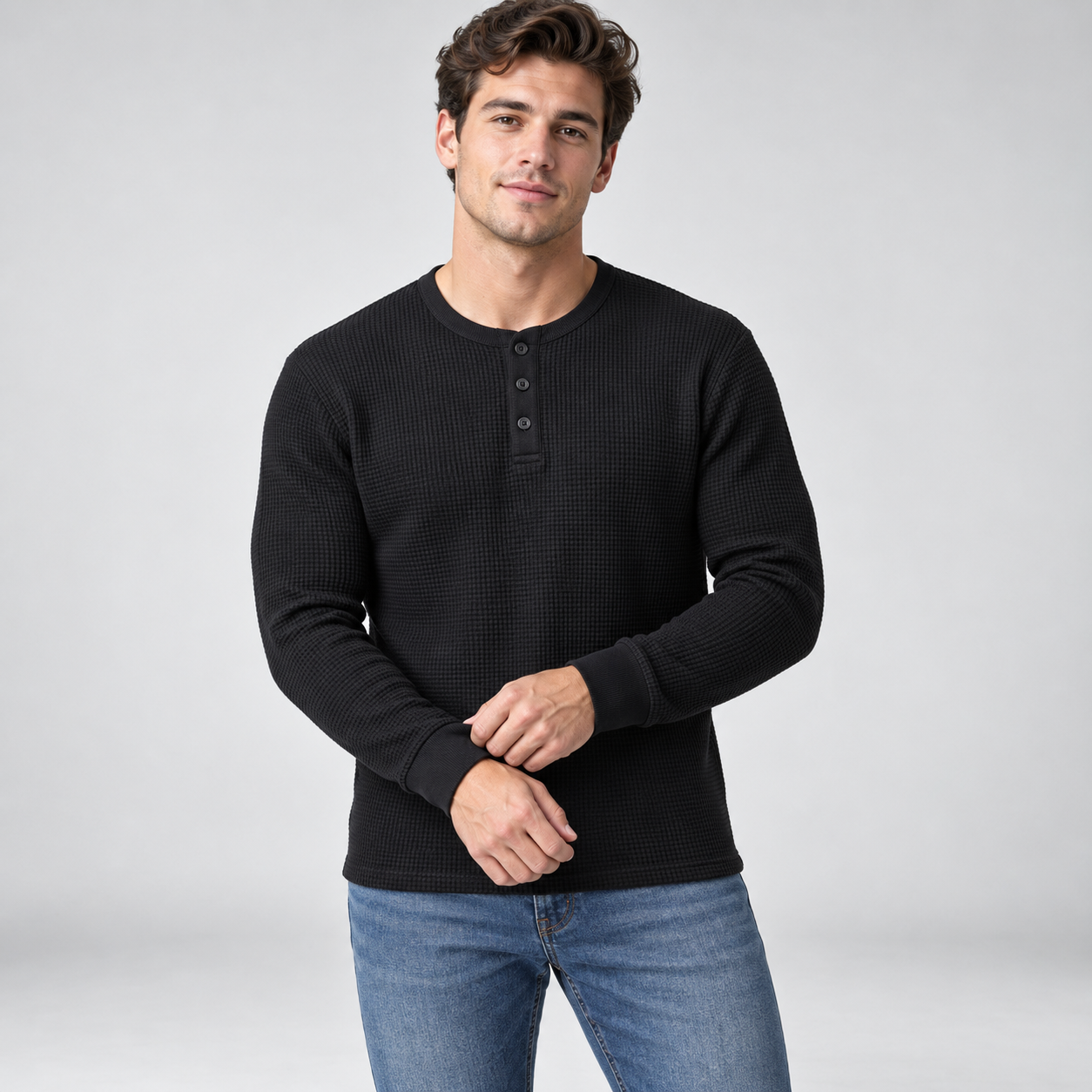 Young American male model wearing Black waffle-knit thermal Henley, front studio view adjusting ribbed cuff