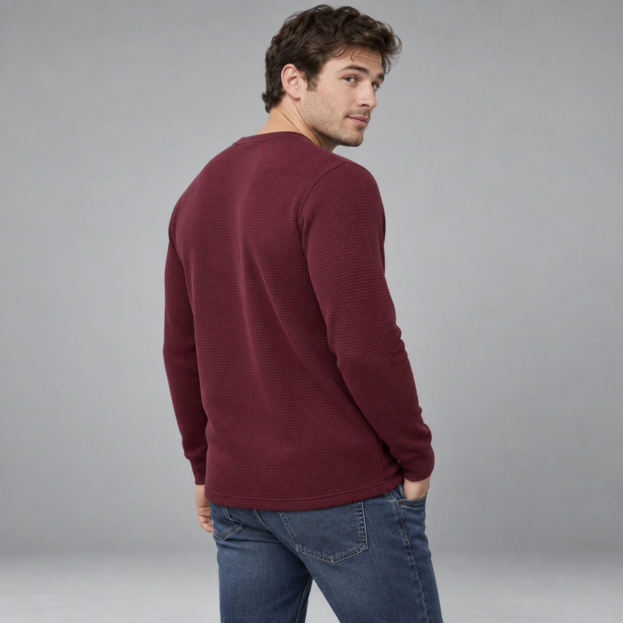Young American male model wearing Burgundy waffle-knit thermal Henley, back three-quarter studio view