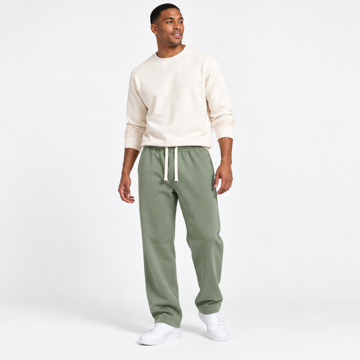 Distinct American male model wearing Sage Green relaxed straight-leg sweatpants in a clean studio, front view