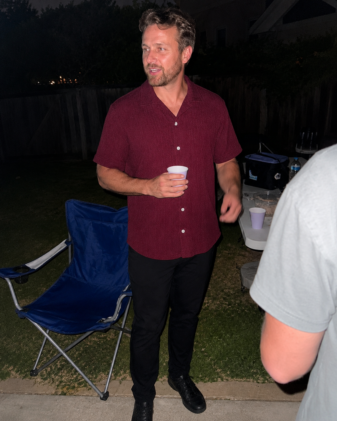 Burgundy textured short-sleeve shirt in a relaxed backyard scene