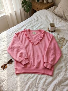 Customer photo: Pink sweatshirt laid out on bed