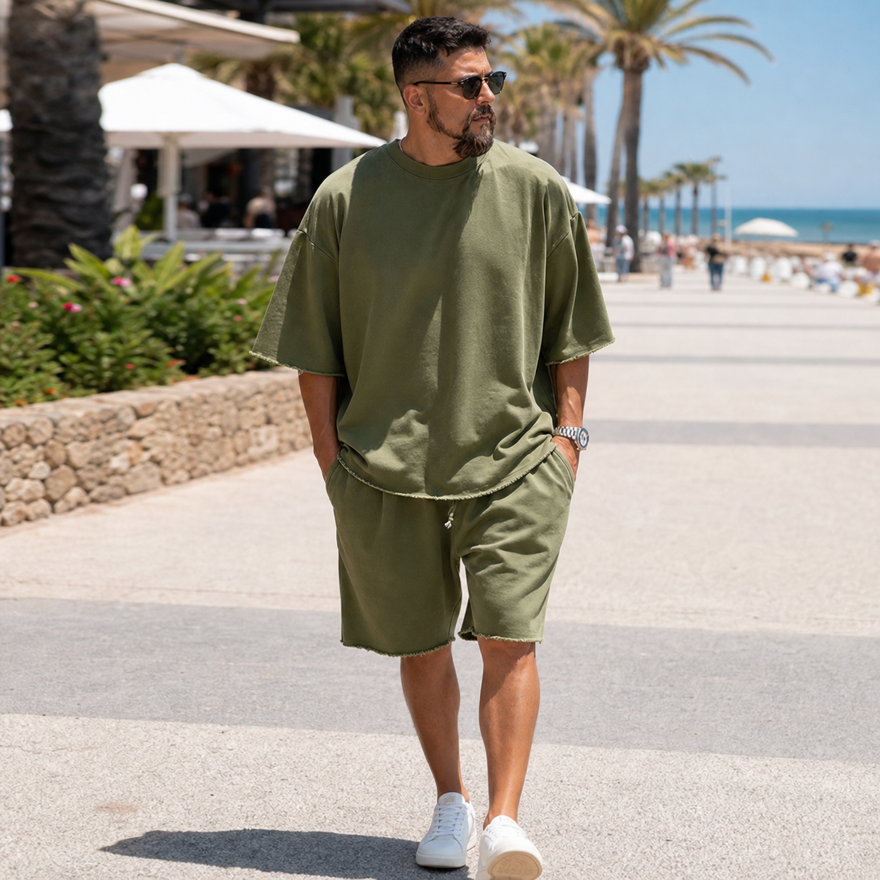 Man wearing an olive loose short sleeve top and shorts set on a sunny boardwalk
