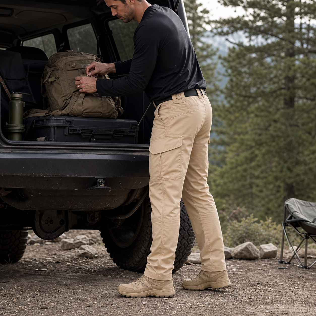 Man wearing khaki tactical ripstop cargo pants while checking a gear bag near an outdoor vehicle