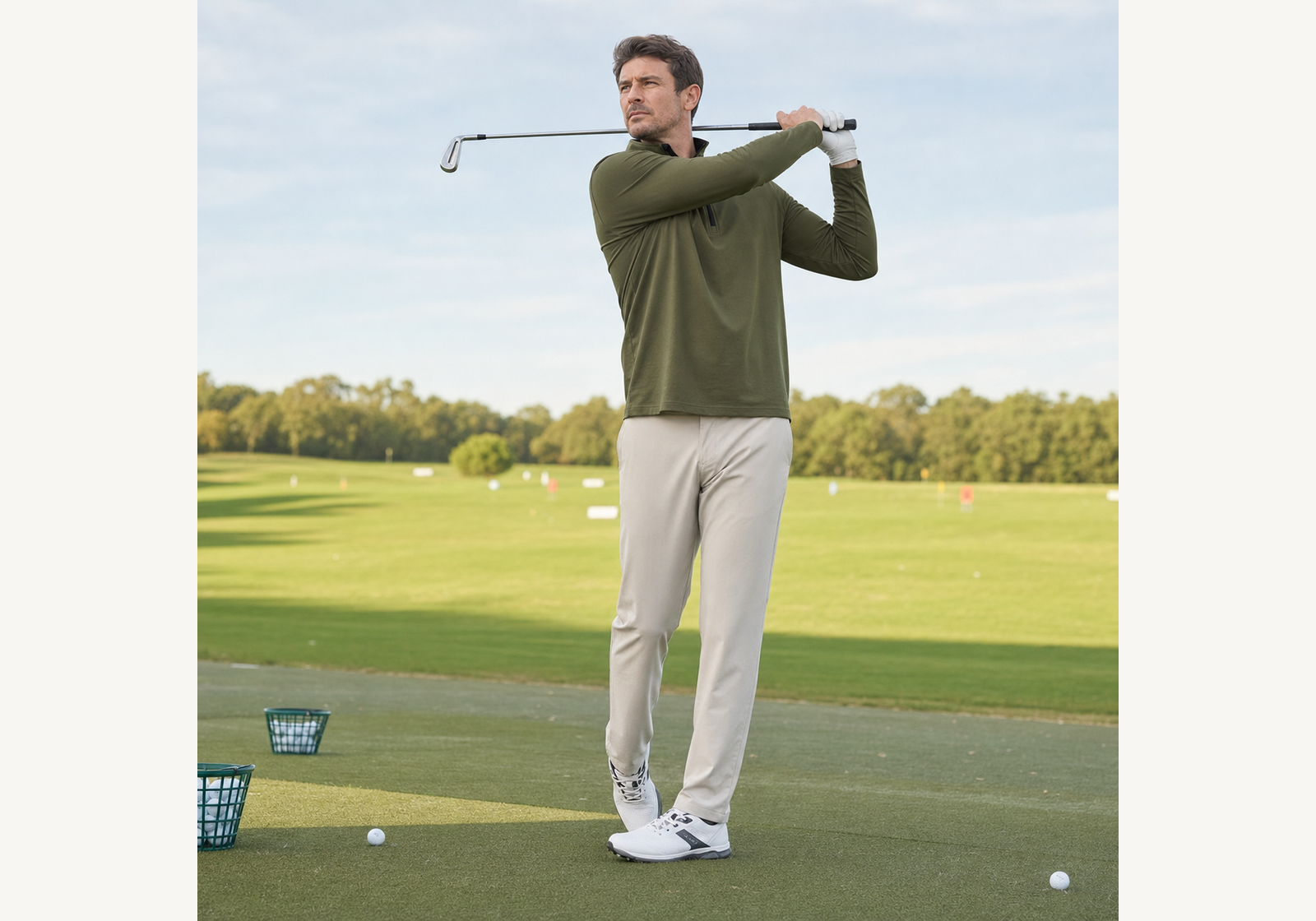 Man wearing an olive quarter zip golf pullover during a golf swing at a driving range