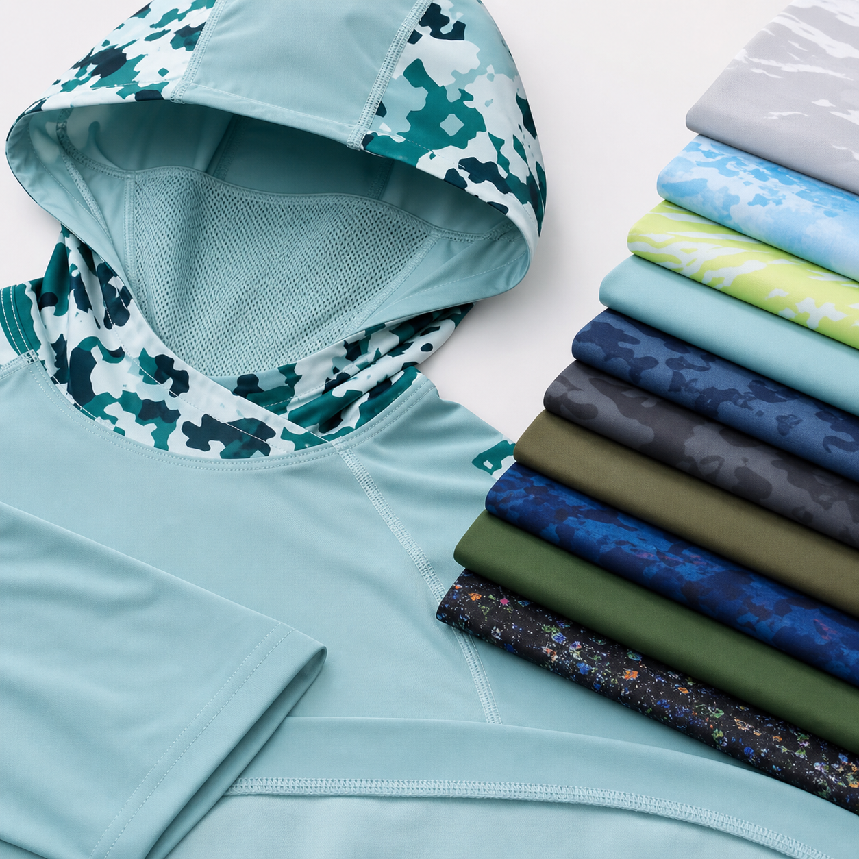 Performance sun hoodie close-up showing hood, face panel, seams, sleeve, hem, and folded color stack