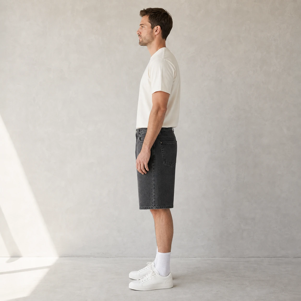 Side view of a model wearing Charcoal Gray denim shorts