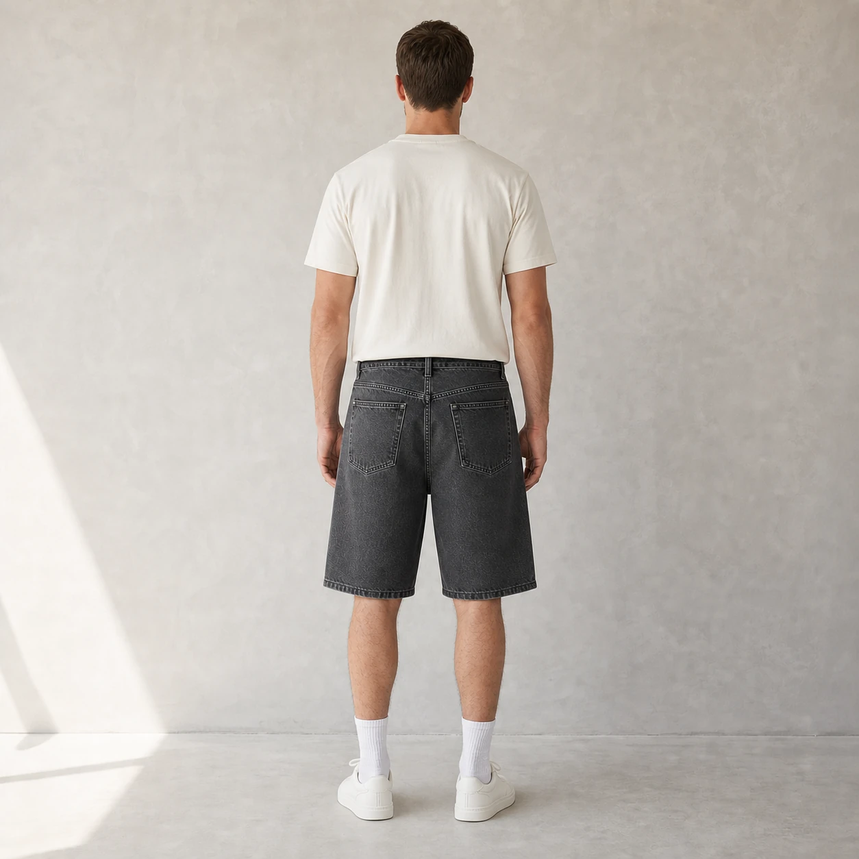 Back view of a model wearing Charcoal Gray denim shorts