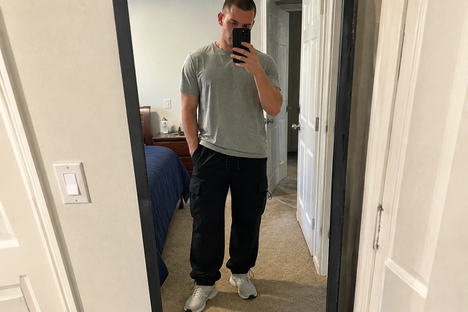 Black parachute cargo pants shown in a casual mirror photo