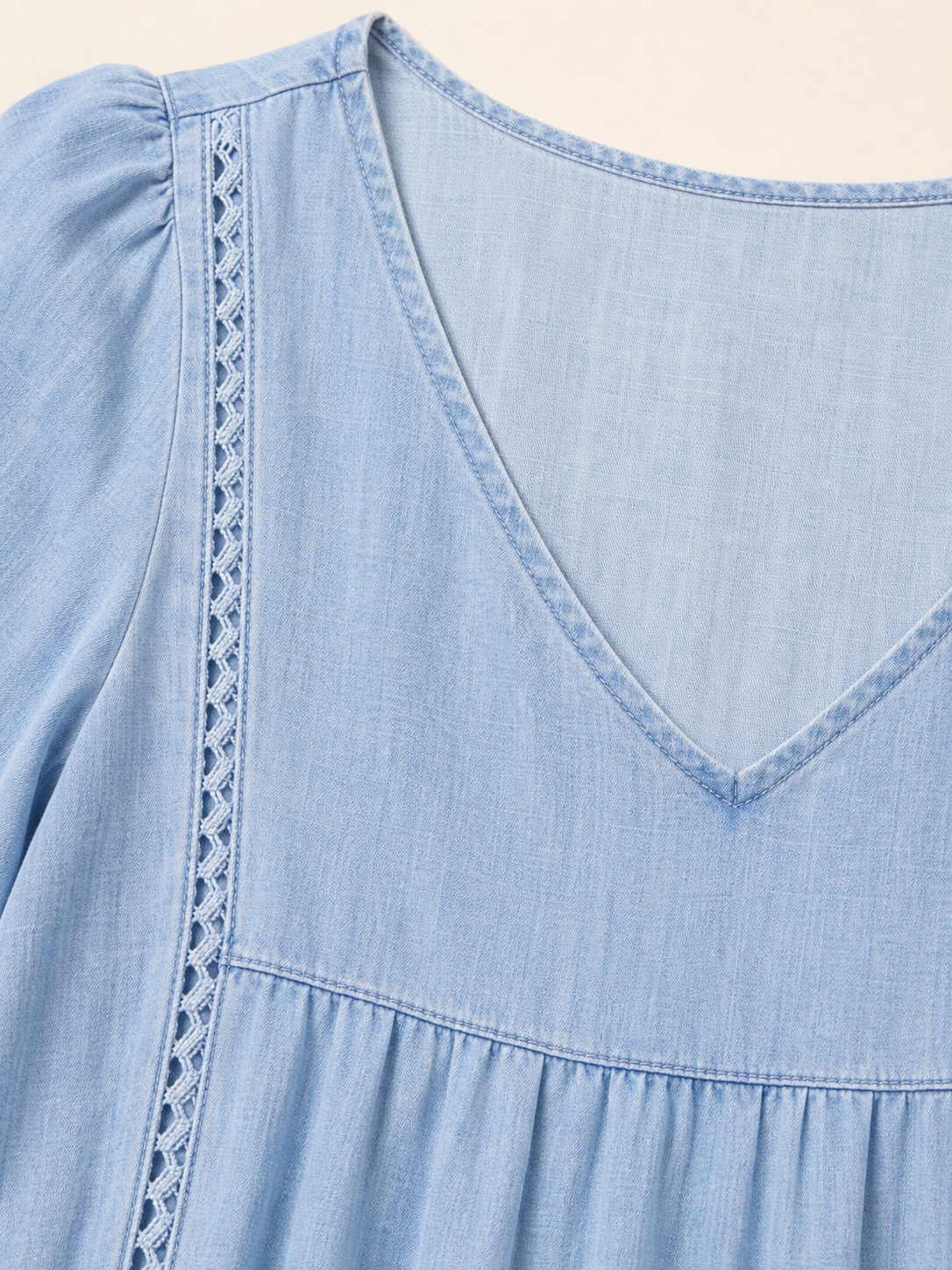 Gros plan sur le col V et la finition ajour&eacute;e de la robe bleu clair