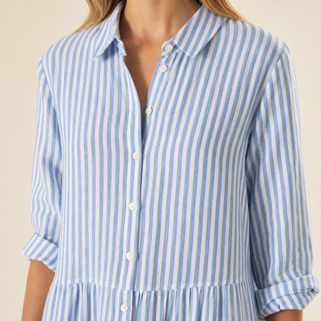 Gros plan du col chemise, des boutons et des manches retroussées de la robe rayée
