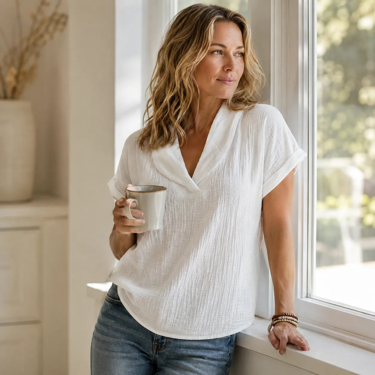 Top Sevella blanc port&eacute; avec un jean dans un int&eacute;rieur lumineux