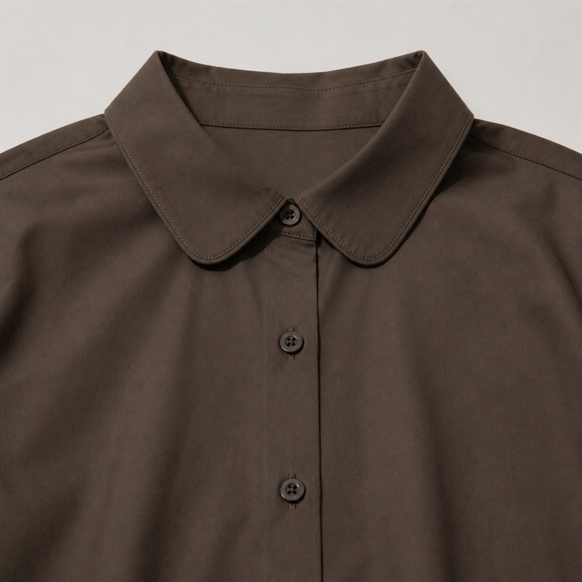 Détail du col arrondi et de la patte de boutonnage sans marque