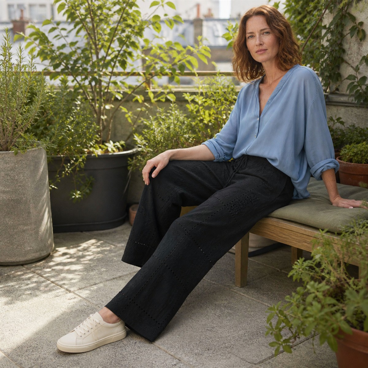 Pantalon noir brodé porté sur une terrasse végétalisée
