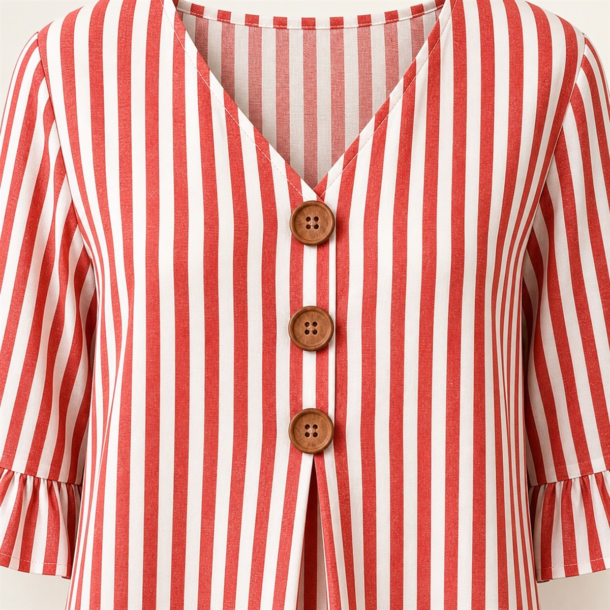 D&eacute;tail du col V, des trois boutons en bois et du pli central de la blouse rouge