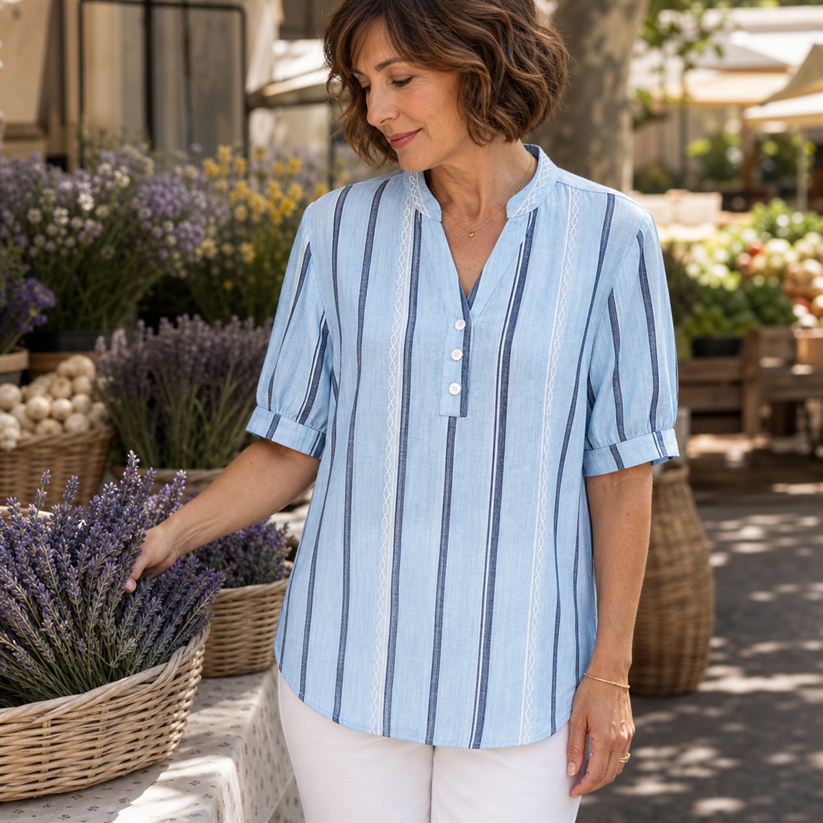 Femme portant le haut Henley bleu ciel rayé dans un marché provençal